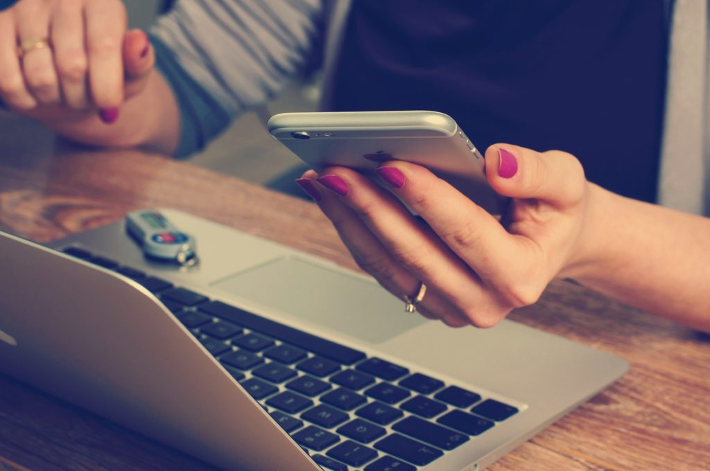 A women checking her phone while working on her laptop